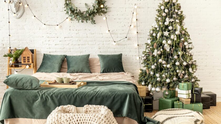 Stylish bedroom decorated with Christmas lights and a tree, creating a warm festive ambiance.