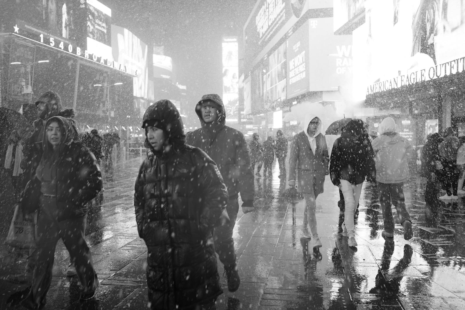 People walking in the snowy streets of Times Square, New York City during winter.