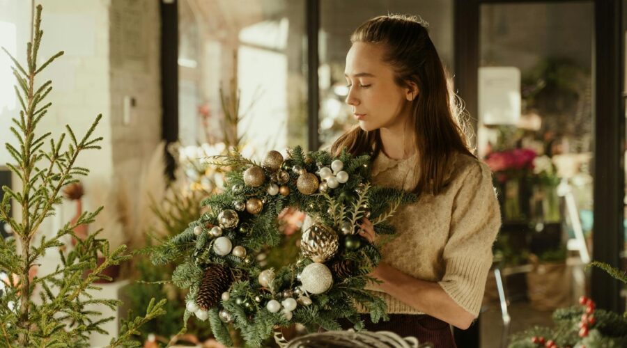 Woman crafting Christmas wreath with ornaments in cozy indoor setting. Perfect holiday season decor image.