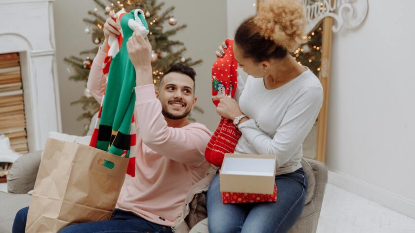 A joyful couple exchanging Christmas presents in a cozy living room.