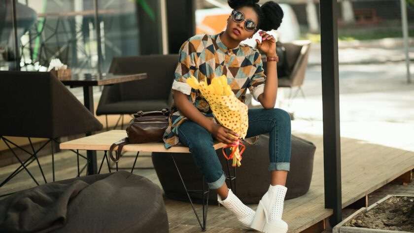 Trendy woman with sunglasses and flowers relaxing on a patio bench in sunlight.