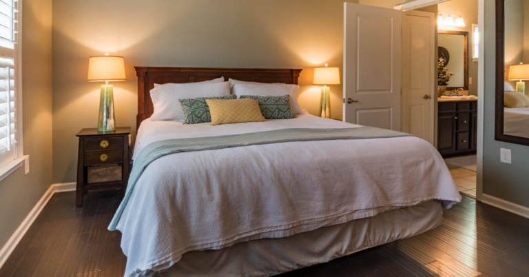 A beautiful white bedroom with gold lights by the side of the bed